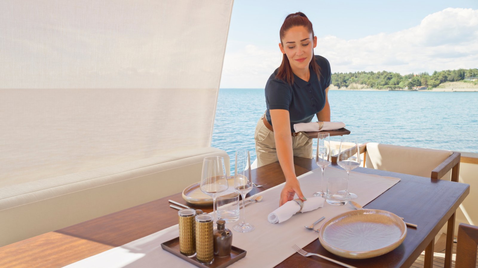Yacht stewardess laying a dining table